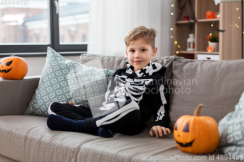 Image of happy boy in halloween costume of skeleton at home