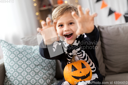 Image of happy boy in halloween costume of skeleton at home