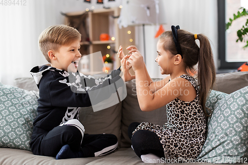 Image of kids in halloween costumes having fun at home