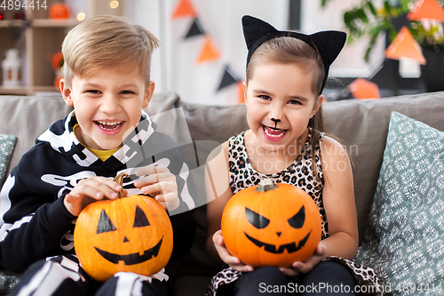 Image of kids in halloween costumes with pumpkins at home