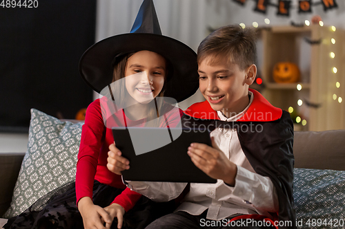 Image of kids in halloween costumes with tablet pc at home