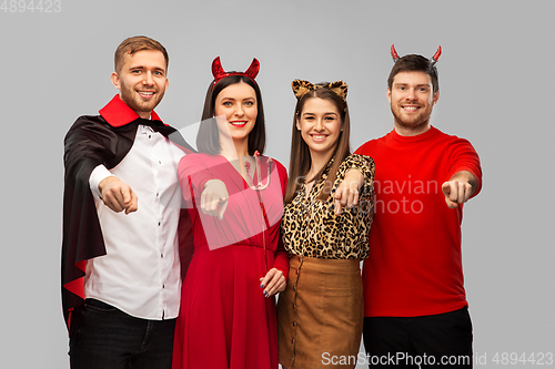 Image of happy friends in halloween costumes over grey