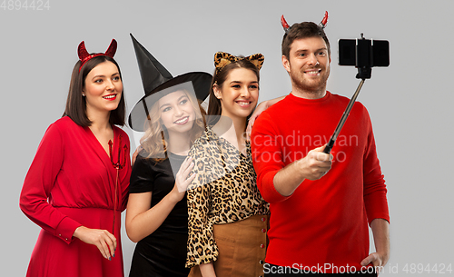 Image of happy friends in halloween costumes taking selfie