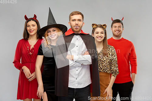 Image of happy friends in halloween costumes over grey