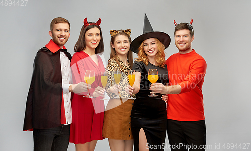 Image of happy friends in halloween costumes over grey