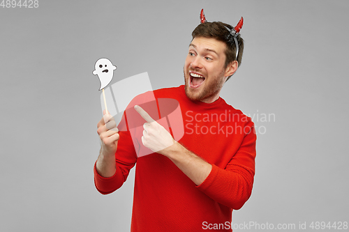 Image of happy man in halloween costume of devil over grey