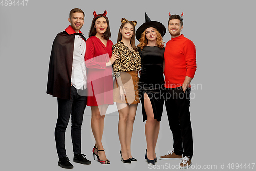 Image of happy friends in halloween costumes over grey