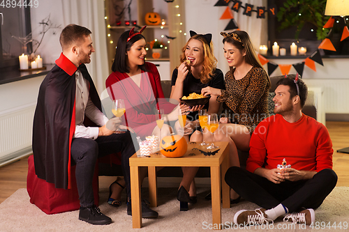 Image of happy friends in halloween costumes at home party