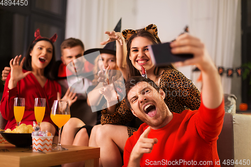 Image of happy friends in halloween costumes taking selfie