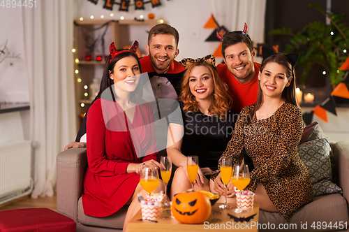 Image of happy friends in halloween costumes at home party