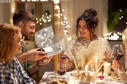 Image of happy friends with red wine at christmas party