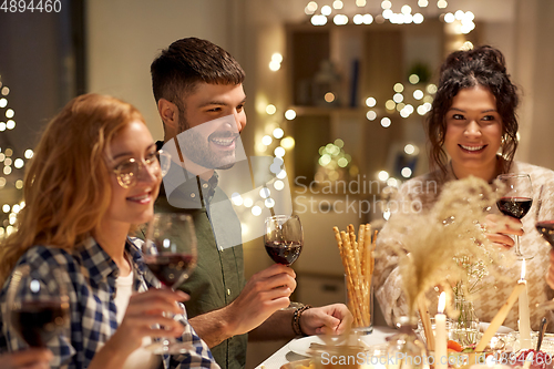 Image of happy friends drinking red wine at christmas party