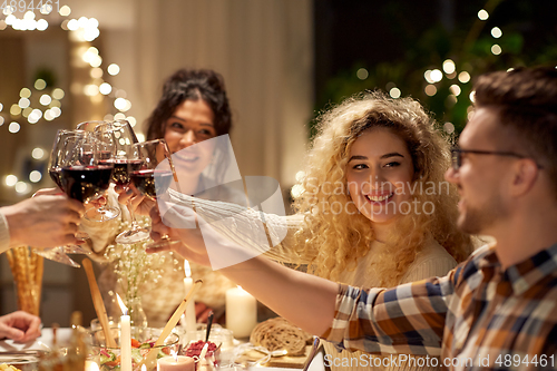 Image of happy friends drinking red wine at christmas party