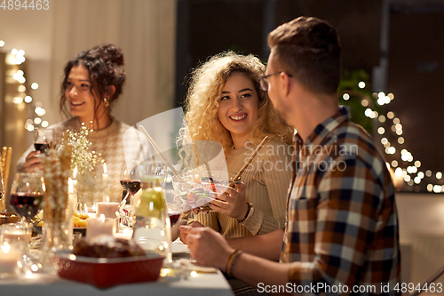 Image of happy friends having christmas dinner at home