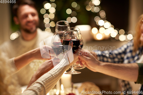 Image of happy friends drinking red wine at christmas party