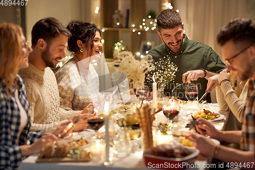 Image of happy friends having christmas dinner at home