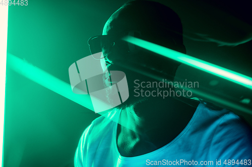 Image of Cinematic portrait of handsome young man in neon lighted room, stylish musician