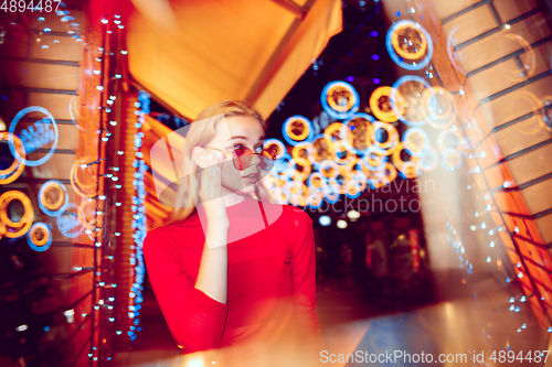 Image of Cinematic portrait of handsome young woman in neon lighted room, stylish musician