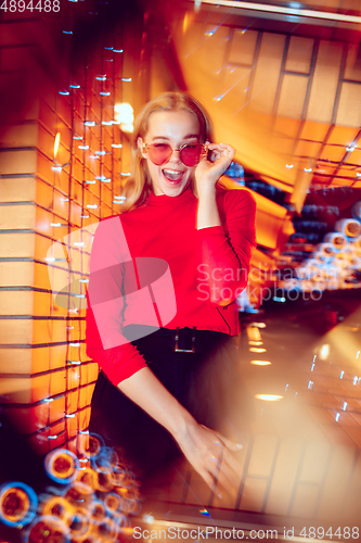 Image of Cinematic portrait of handsome young woman in neon lighted room, stylish musician