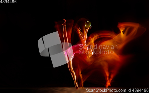 Image of Young flexible female gymnast isolated on black studio background in mixed light,