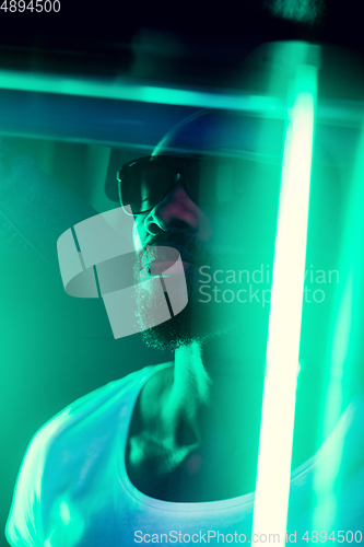 Image of Cinematic portrait of handsome young man in neon lighted room, stylish musician