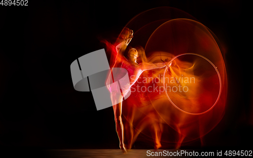 Image of Young flexible female gymnast isolated on black studio background in mixed light,
