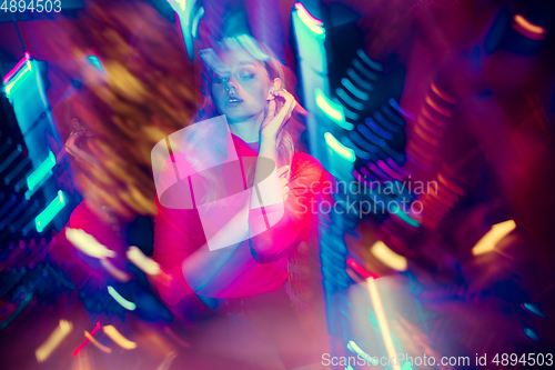 Image of Cinematic portrait of handsome young woman in neon lighted room, stylish musician