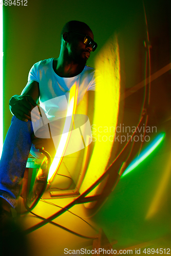 Image of Cinematic portrait of handsome young man in neon lighted room, stylish musician