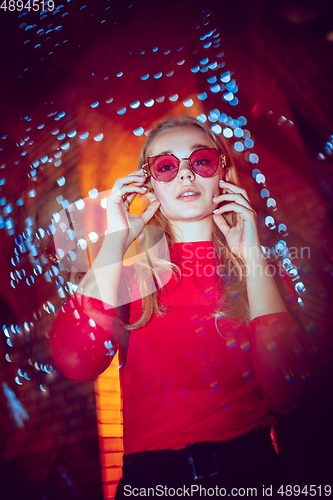 Image of Cinematic portrait of handsome young woman in neon lighted room, stylish musician