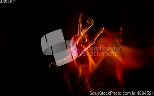 Image of Young flexible female gymnast isolated on black studio background in mixed light,