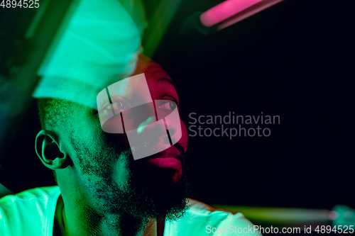 Image of Cinematic portrait of handsome young man in neon lighted room, stylish musician