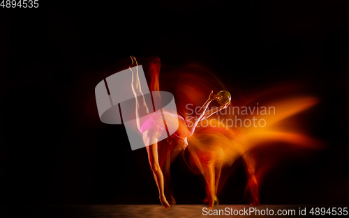 Image of Young flexible female gymnast isolated on black studio background in mixed light,