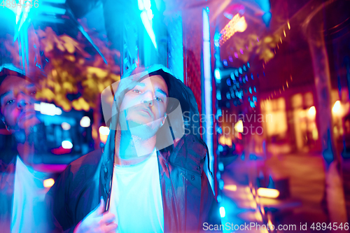 Image of Cinematic portrait of handsome young man in neon lighted room, stylish musician