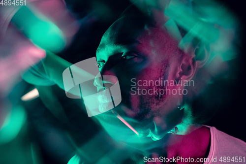 Image of Cinematic portrait of handsome young man in neon lighted room, stylish musician