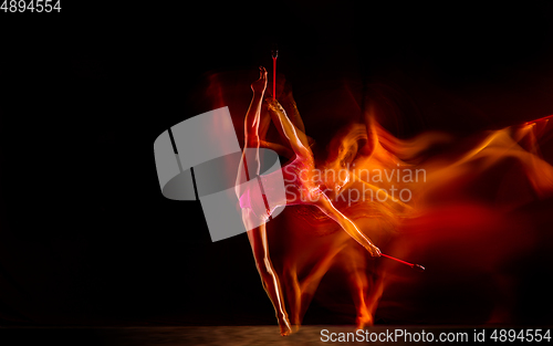 Image of Young flexible female gymnast isolated on black studio background in mixed light,