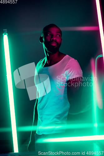 Image of Cinematic portrait of handsome young man in neon lighted room, stylish musician