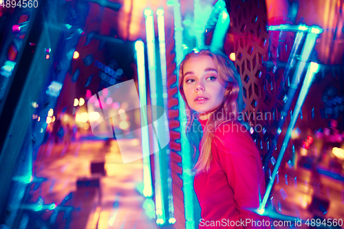 Image of Cinematic portrait of handsome young woman in neon lighted room, stylish musician