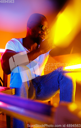 Image of Cinematic portrait of handsome young man in neon lighted room, stylish musician