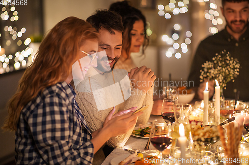 Image of friends with cellphone having dinner party at home