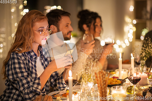 Image of woman with smartphone at dinner party with friends