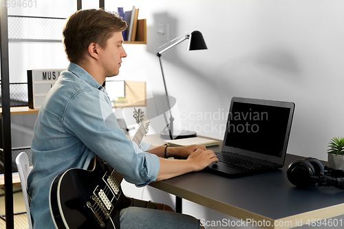 Image of young man with laptop and bass guitar at home