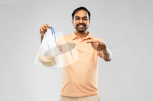 Image of happy man holding reusable string bag with bananas