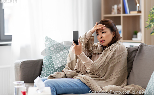 Image of sick asian woman with smartphone at home