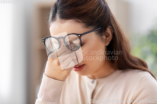 Image of tired woman with glasses rubbing her nose bridge