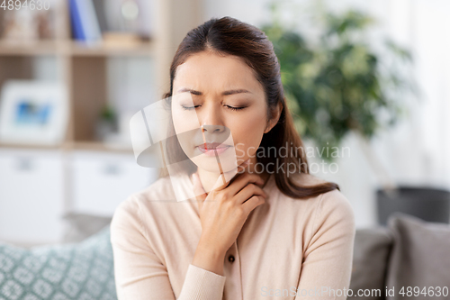 Image of sick asian woman with sore throat at home
