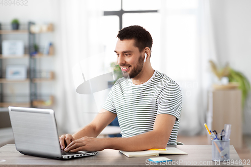 Image of man with laptop and earphones at home office