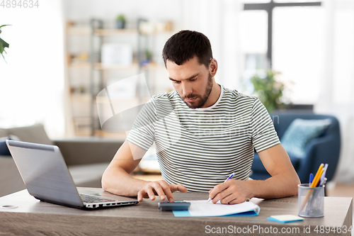 Image of man with files and calculator works at home office