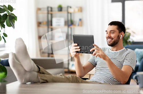 Image of happy man with tablet pc and earphones at home