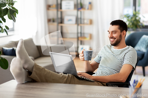 Image of happy man with laptop drinking coffee at home