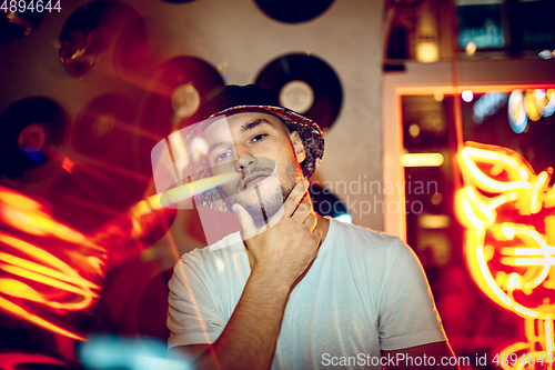 Image of Cinematic portrait of handsome young man in neon lighted room, stylish musician